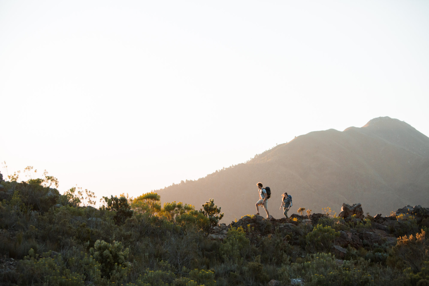 Hikers walking along mountain trail at sunrise