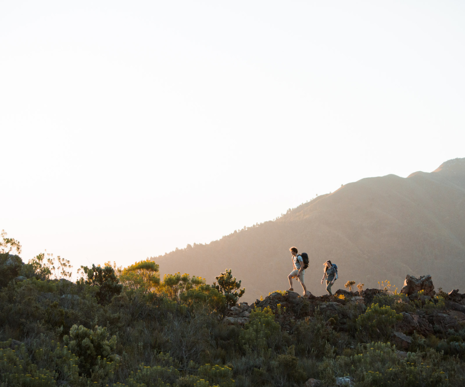 Hikers walking along mountain trail at sunrise