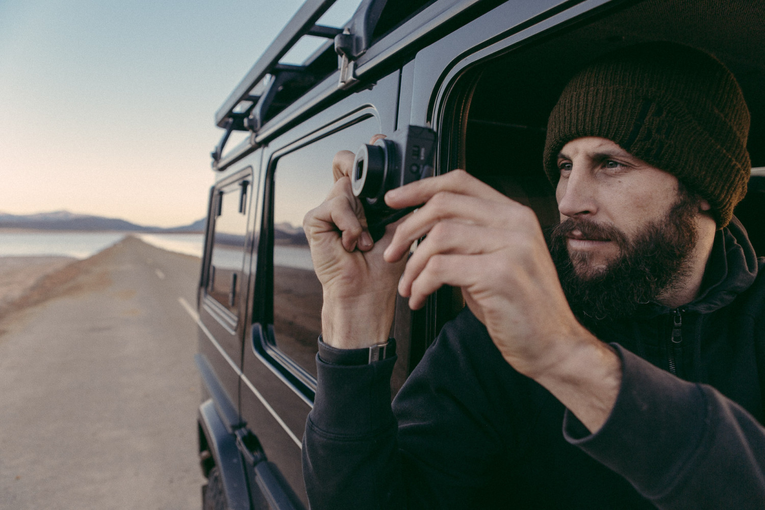 Man taking photo from vehicle near lake