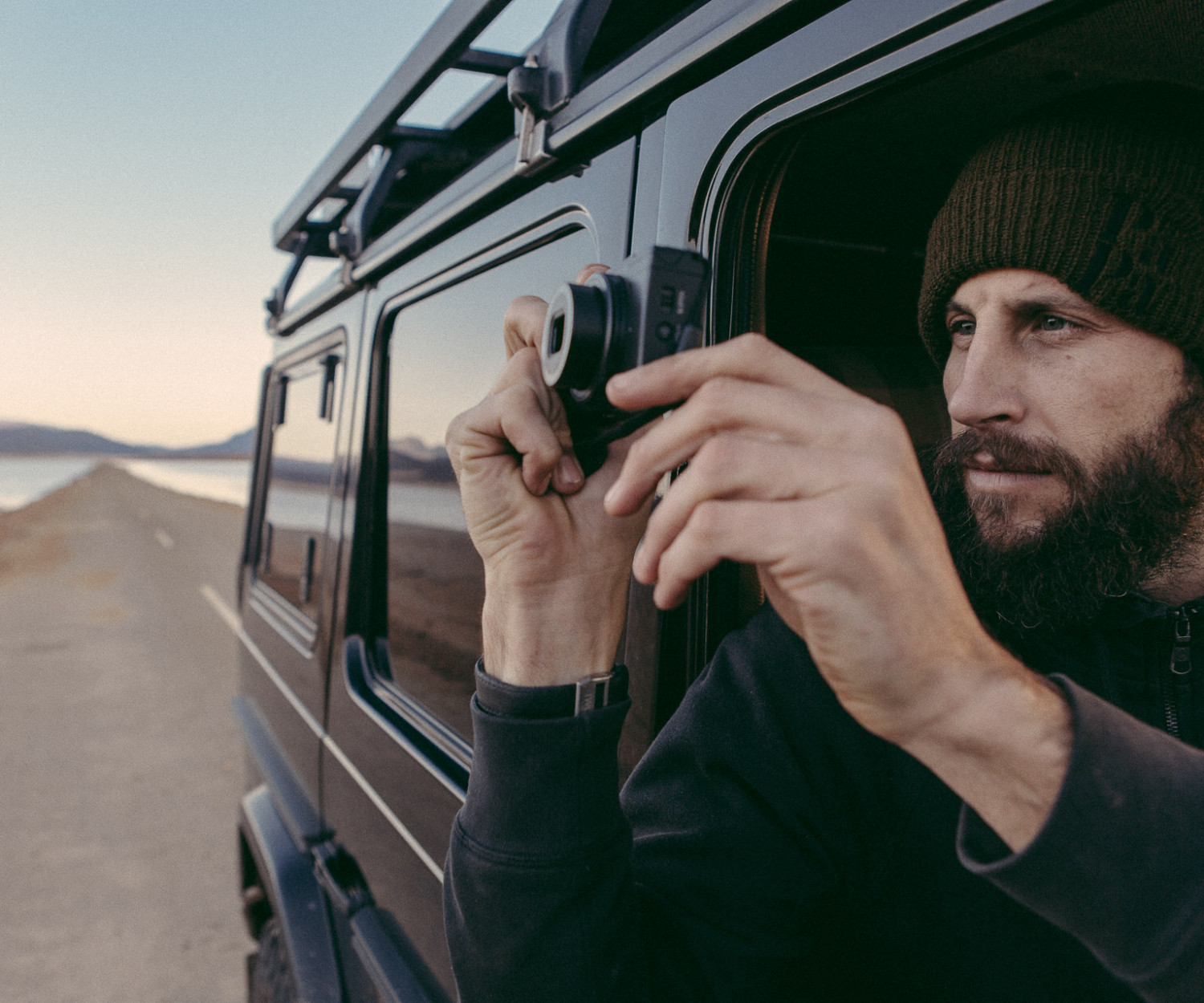 Man taking photo from vehicle near lake