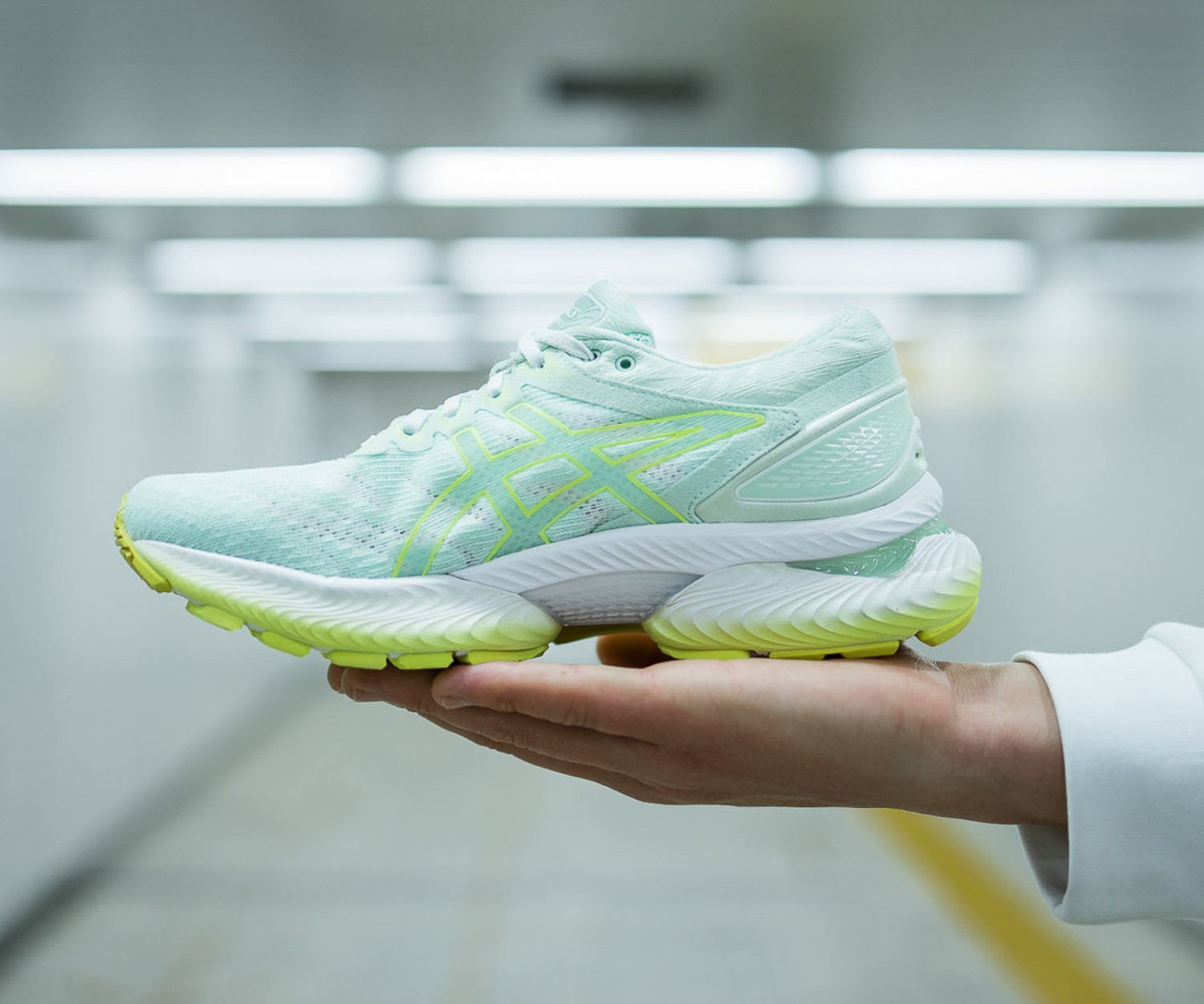 Mint green running shoe held in hand.