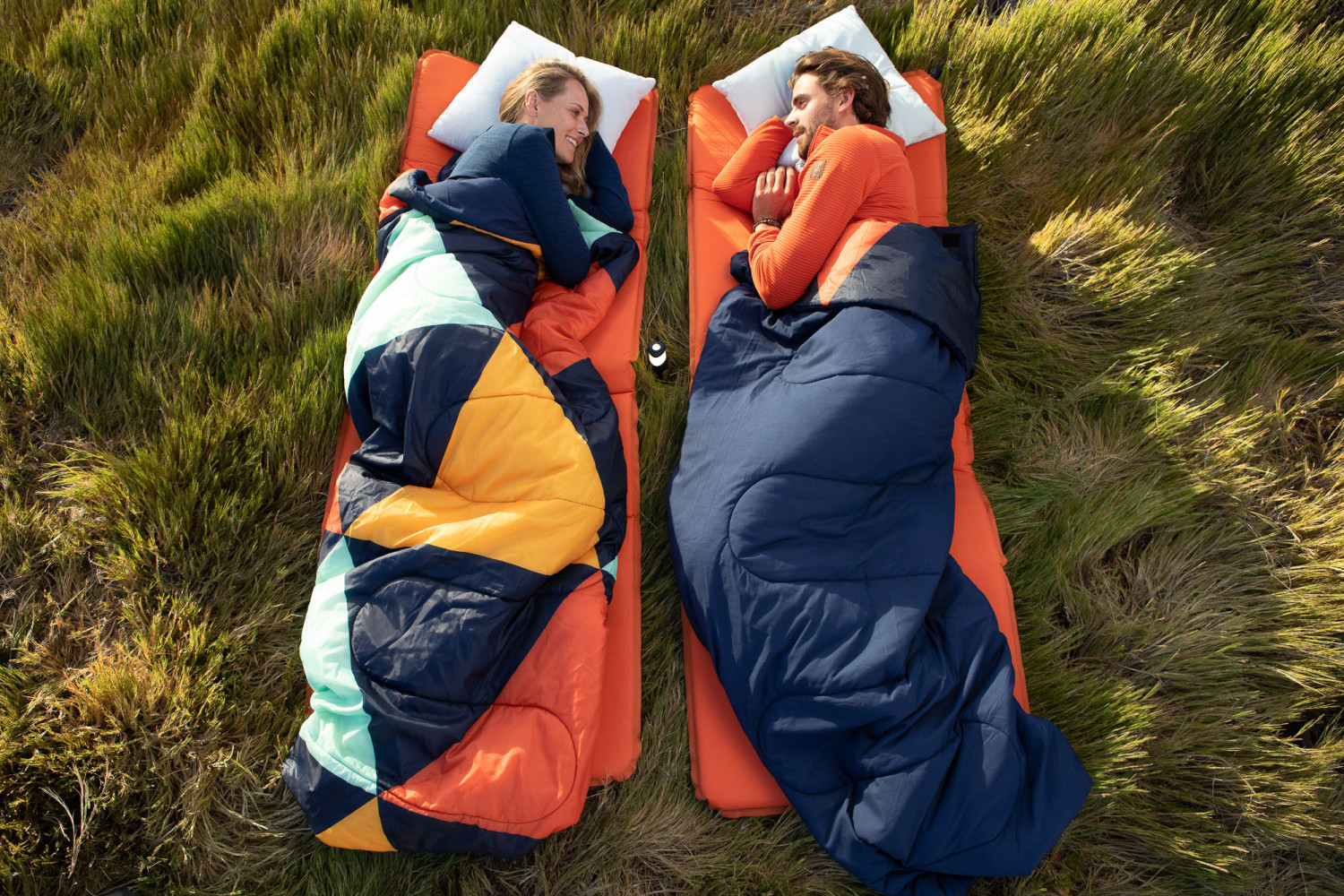 Couple camping in sleeping bags on grass