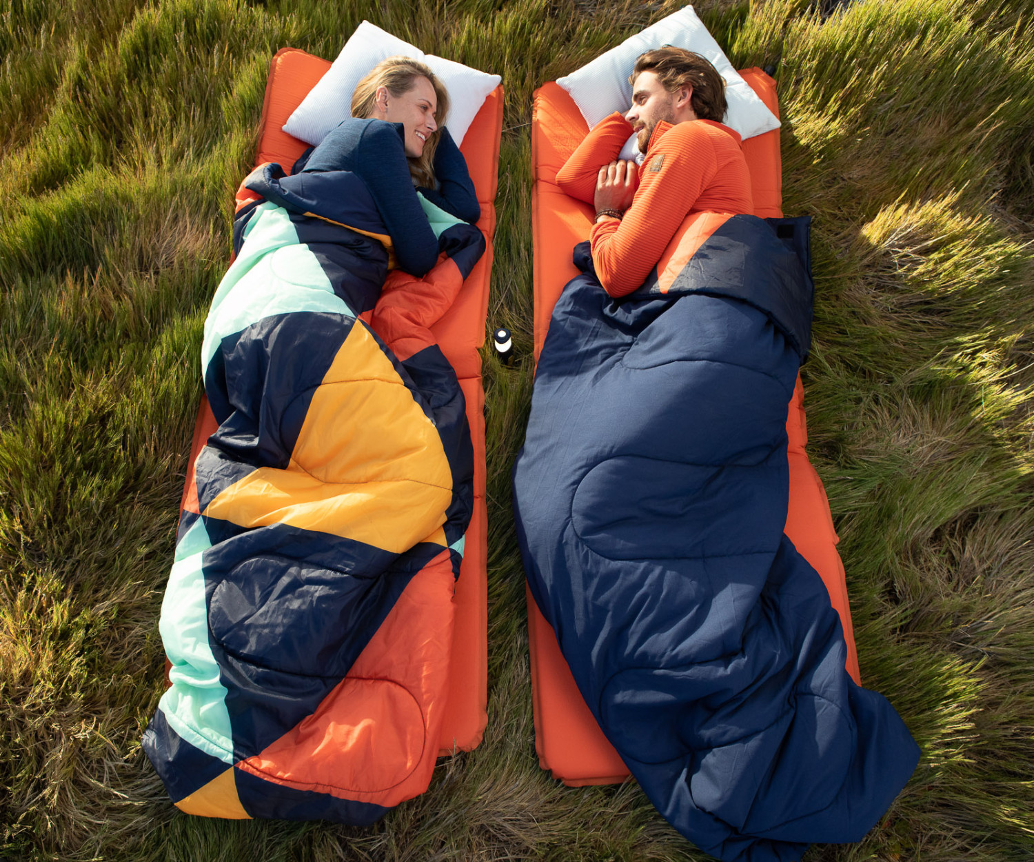 Couple camping in sleeping bags on grass