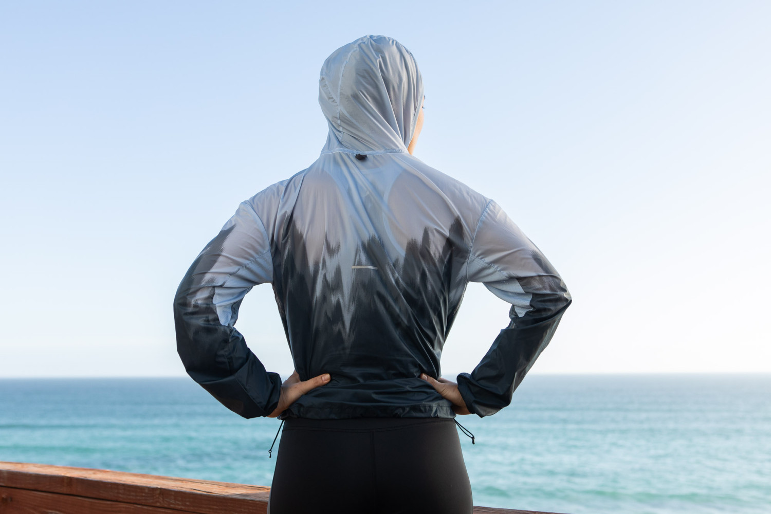 Person in hooded jacket by the ocean