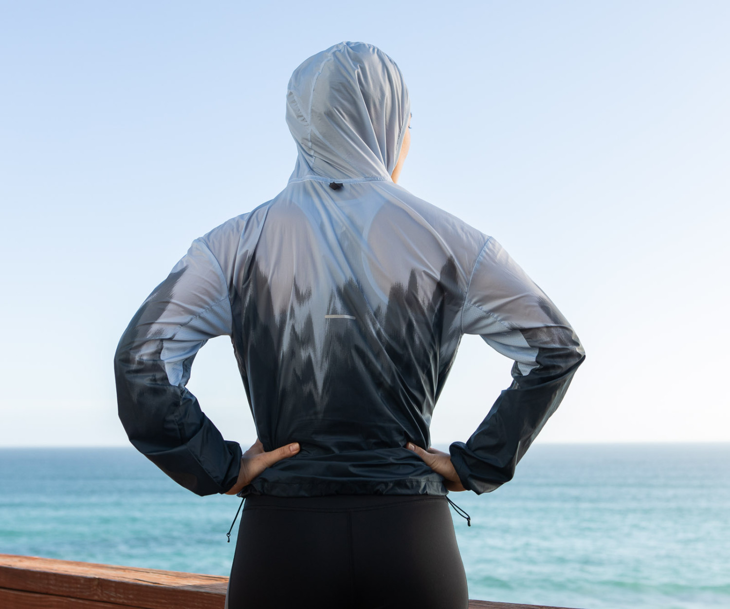 Person in hooded jacket by the ocean