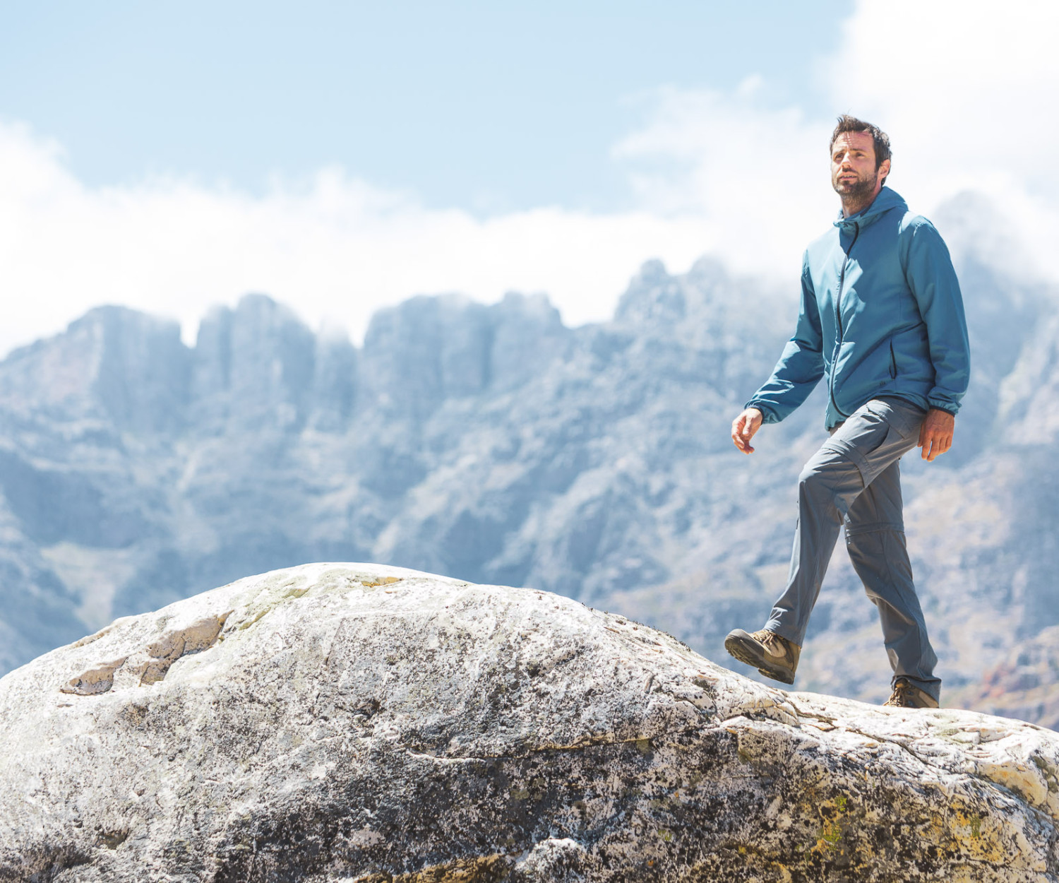 Man hiking on rock with mountains background
