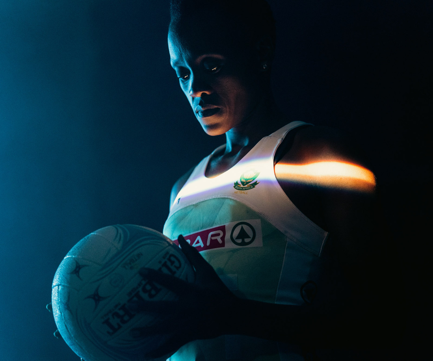 Athlete holding netball in dramatic lighting scene