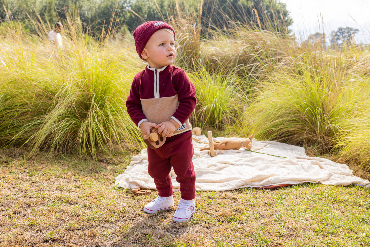 Toddler playing outdoors with wooden toy car
