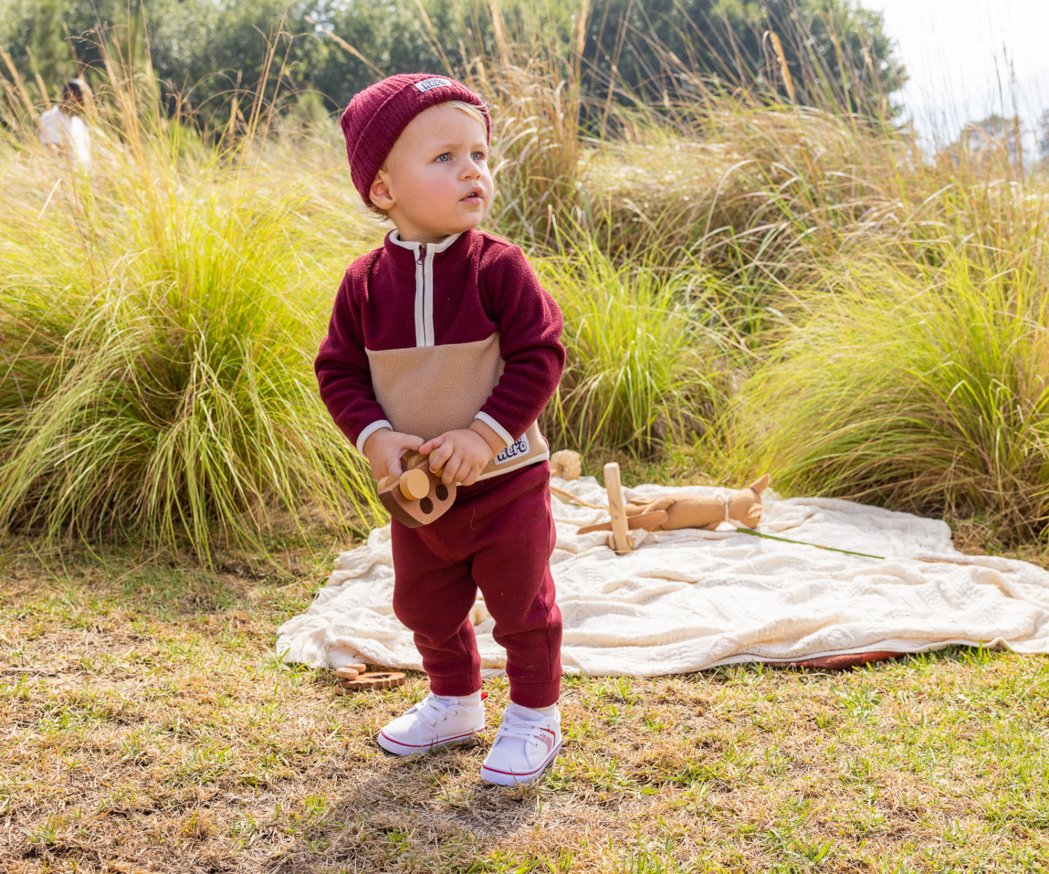 Toddler playing outdoors with wooden toy car