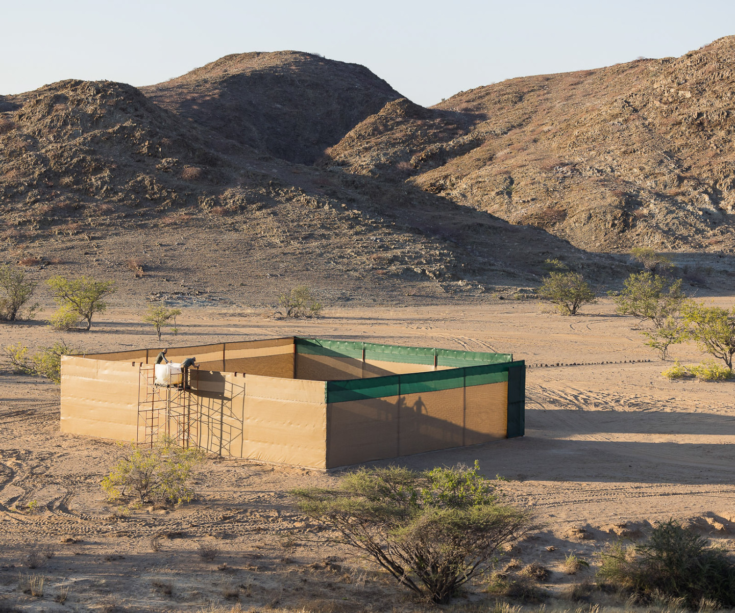 African Parks conservation: Habitat structure in arid landscape with mountains. Staff on ladder.