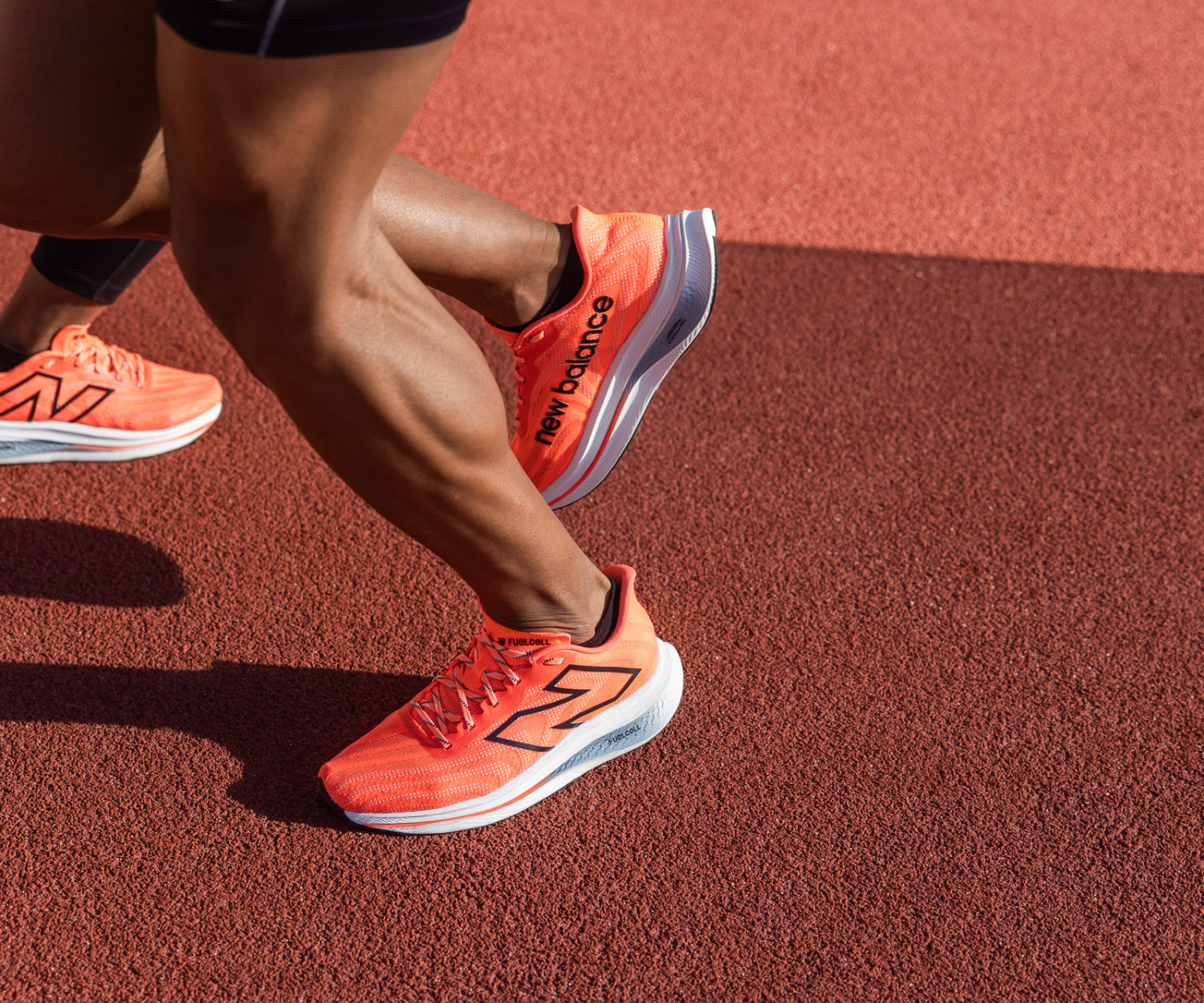 Runners wearing orange shoes on track.