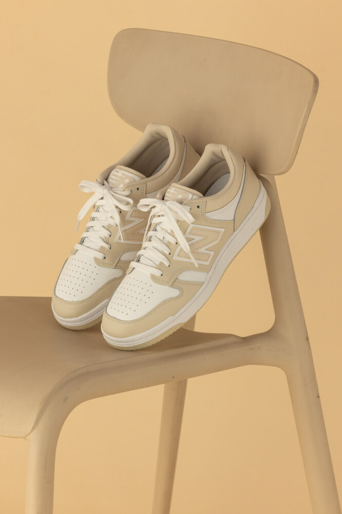 Product photography of the stylish New Balance BB480 sneakers in cream and white.

