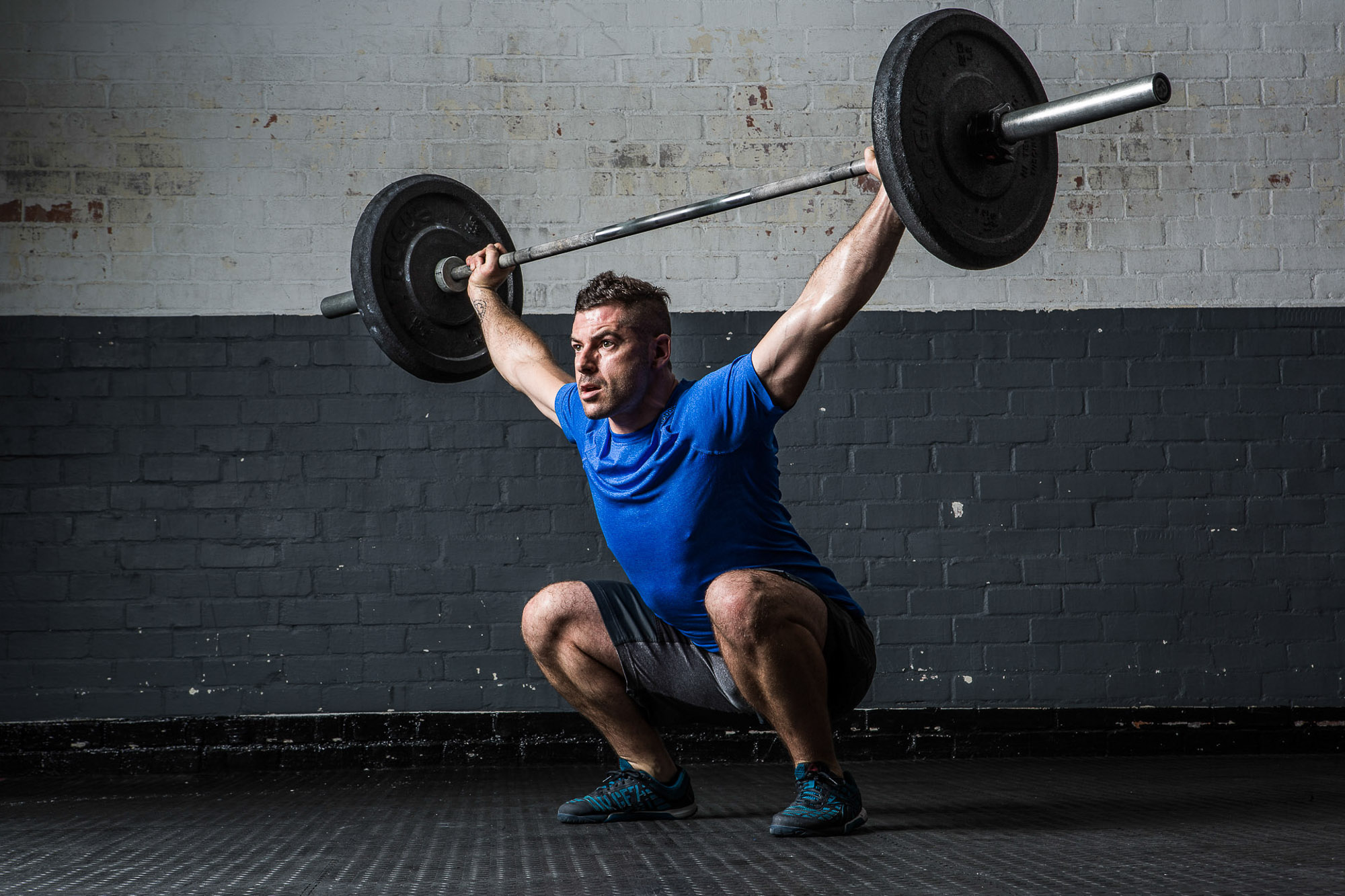 Man lifting weights in gym squat position by Cape Town photographer Casey Crafford