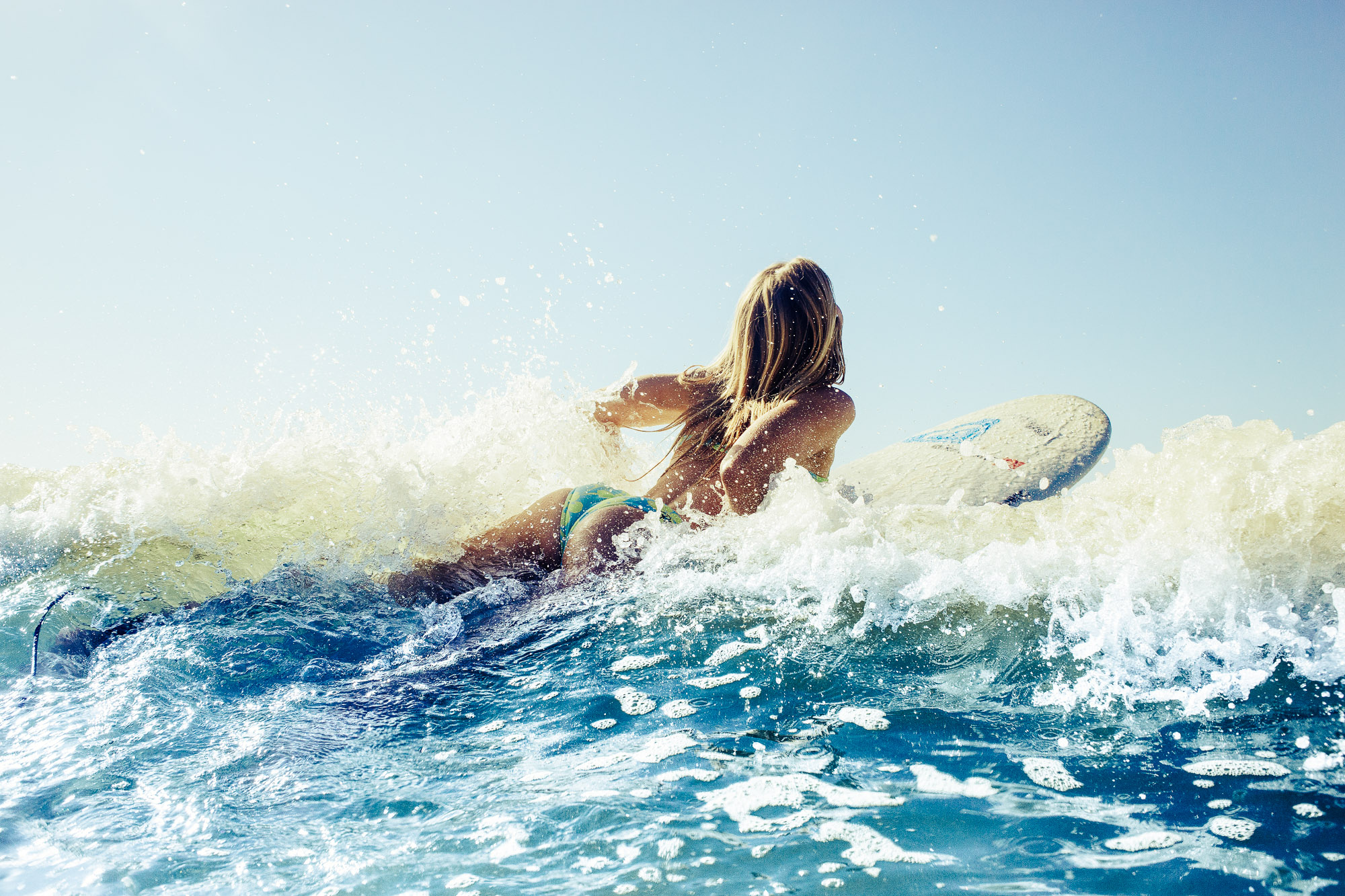 Surfer paddles through ocean waves by Cape Town photographer Casey Crafford