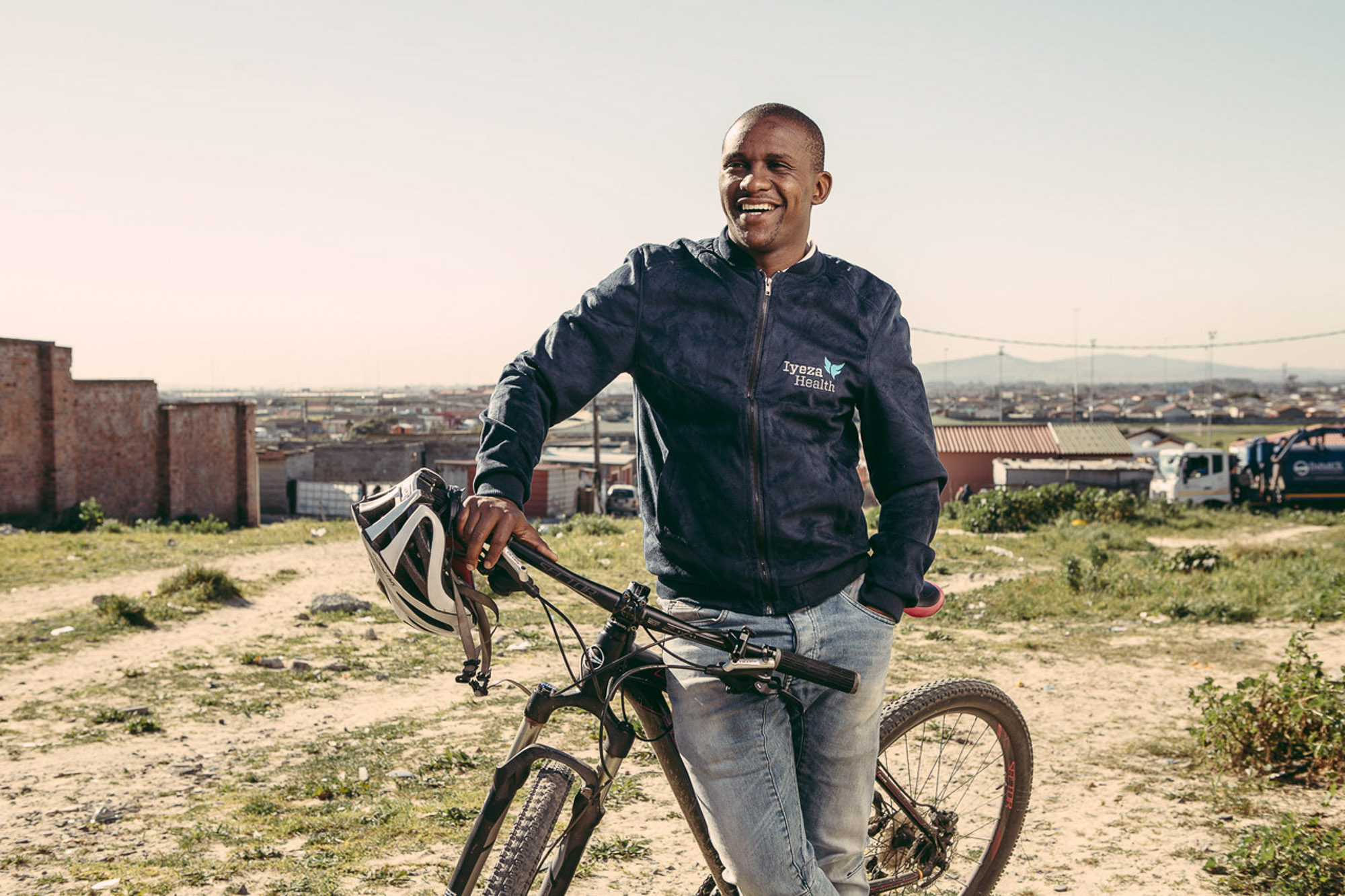 Man smiling next to his bicycle outdoors by Cape Town photographer Casey Crafford